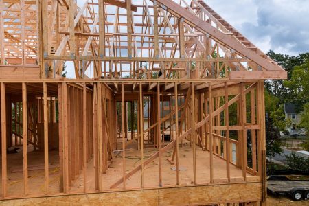 Condominium building with under construction wooden house with timber framing
